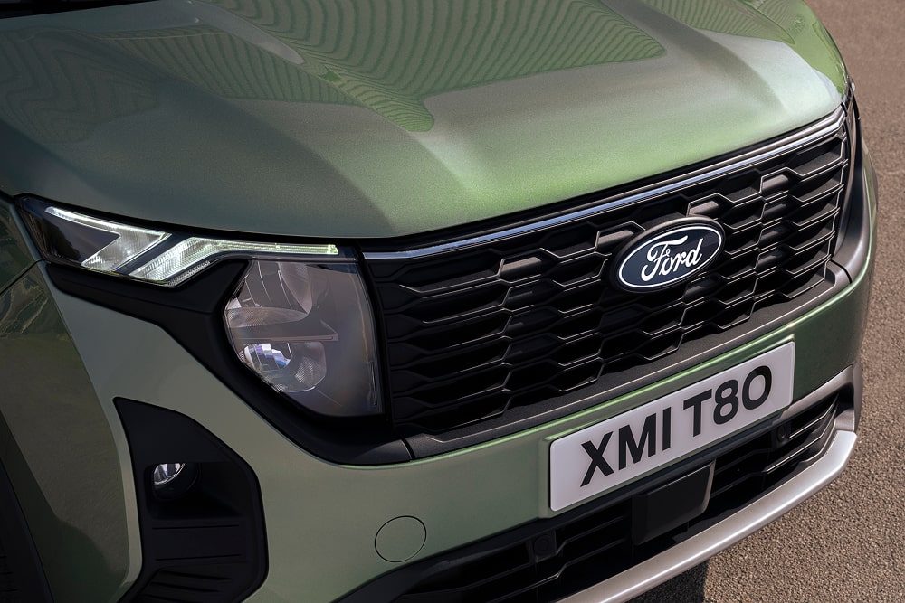 Detalle de la rejilla delantera y del faro de un monovolumen Ford Tourneo Courier verde.