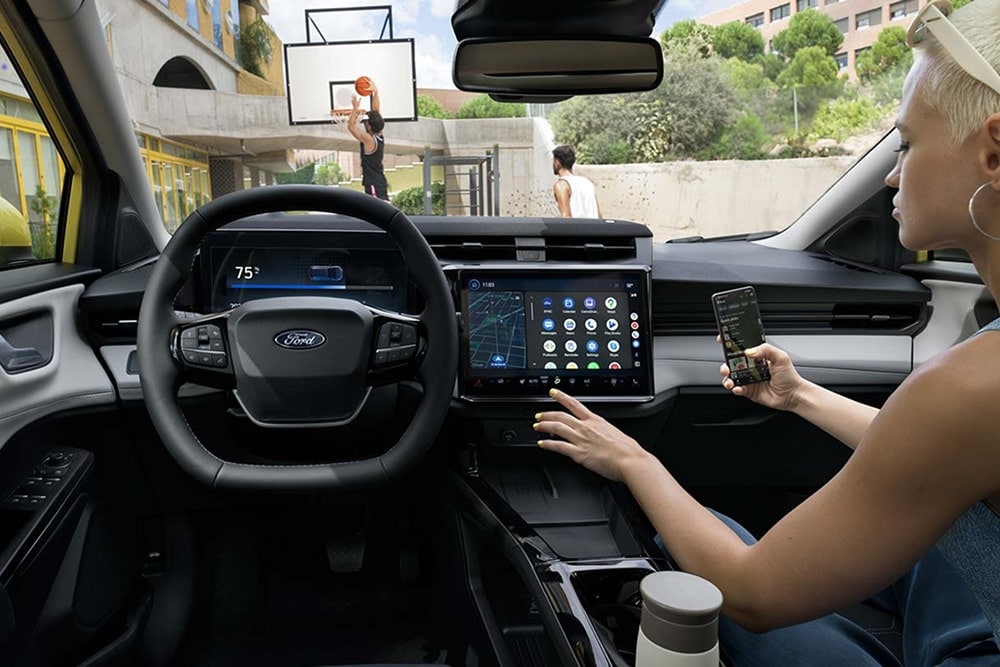 Interior de un coche pequeño Ford Puma Gen-E e imagen del sapicadero y los controles de la pantalla táctil.