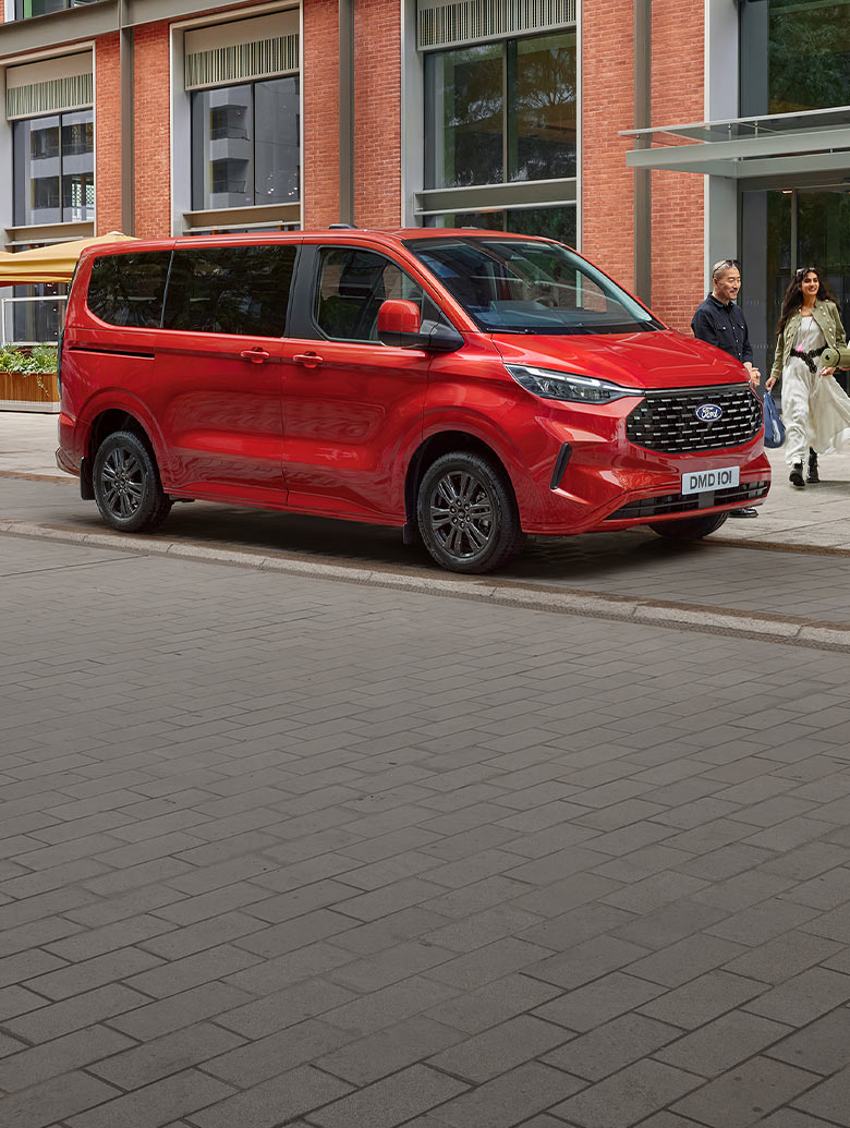 Un Ford Tourneo Custom rojo aparcada en una calle de una ciudad.