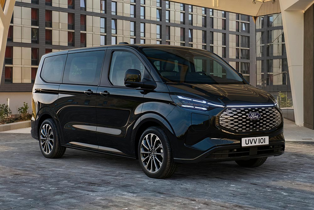 Una Ford E-Tourneo Custom negra estacionada frente a un edificio moderno.