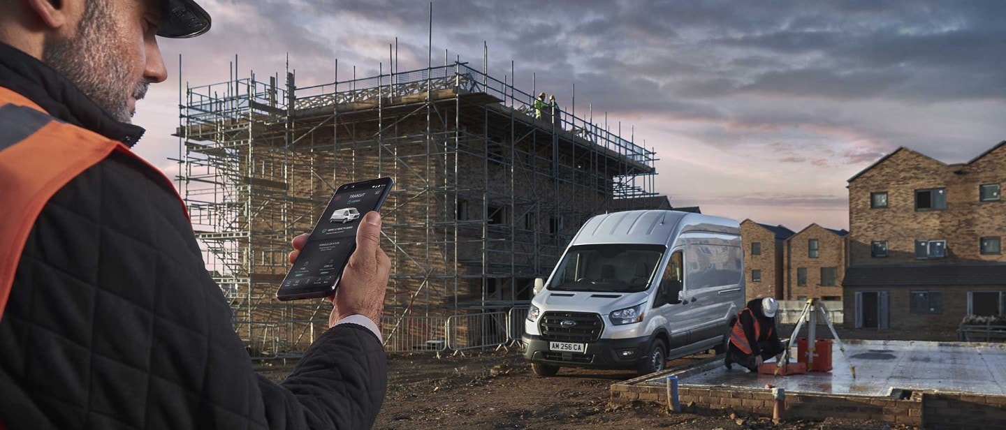Transit Van in the middle of building site with builder checking phone with FordPass app