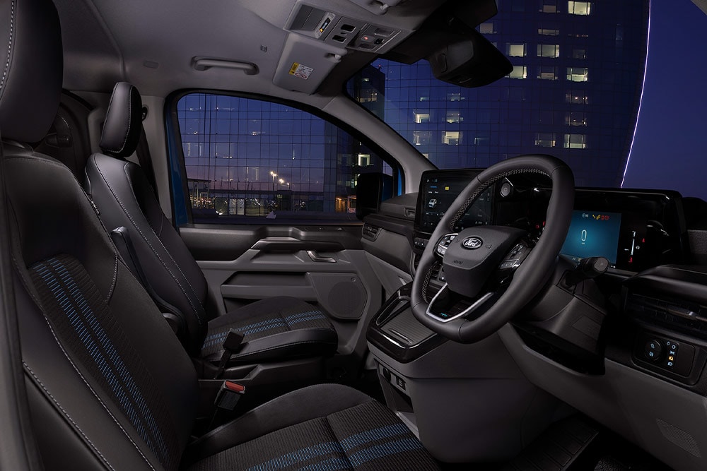 Interior de una furgoneta eléctrica Ford E-Transit Custom con asientos para conductor y pasajero.