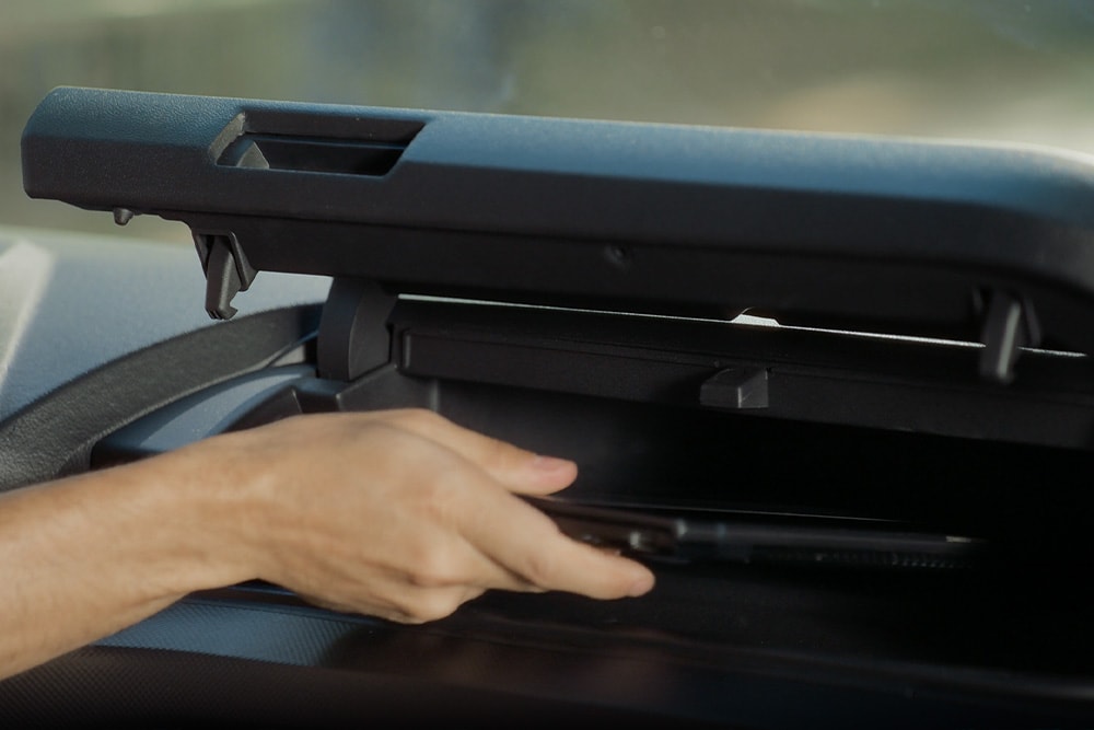 Una mano abriendo un compartimento de almacenamiento en una furgoneta eléctrica Ford E-Transit Custom.