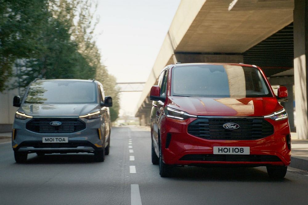 Una furgoneta Ford Transit Custom gris y roja circulando por una autopista.