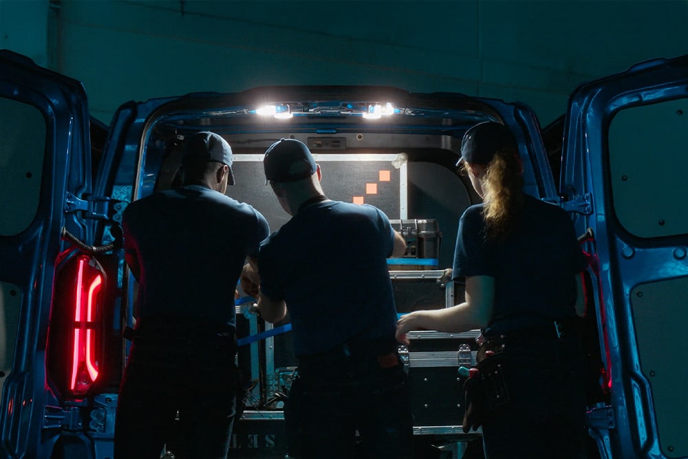 Tres personas trabajando en la parte trasera de una furgoneta eléctrica Ford E-Transit Custom.