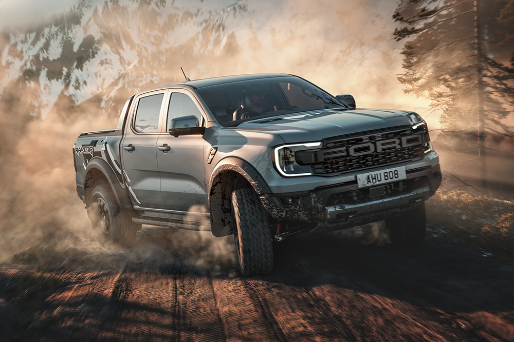 Un Ford Ranger Raptor circula en modo de conducción Baja por un camino de tierra, con un paisaje pintoresco de fondo.