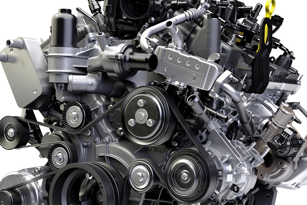 Primer plano del motor de un vehículo, en el que se muestran varias correas, poleas y otros componentes mecánicos.