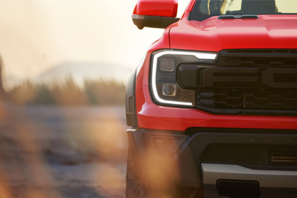 Primer plano de la rejilla delantera de un Ford Ranger Raptor rojo.