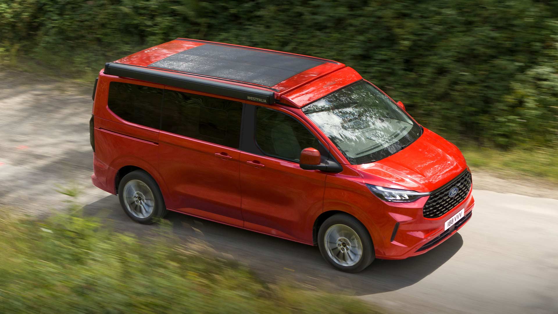 Ford Transit Custom Nugget roja circulando por un camino de tierra.