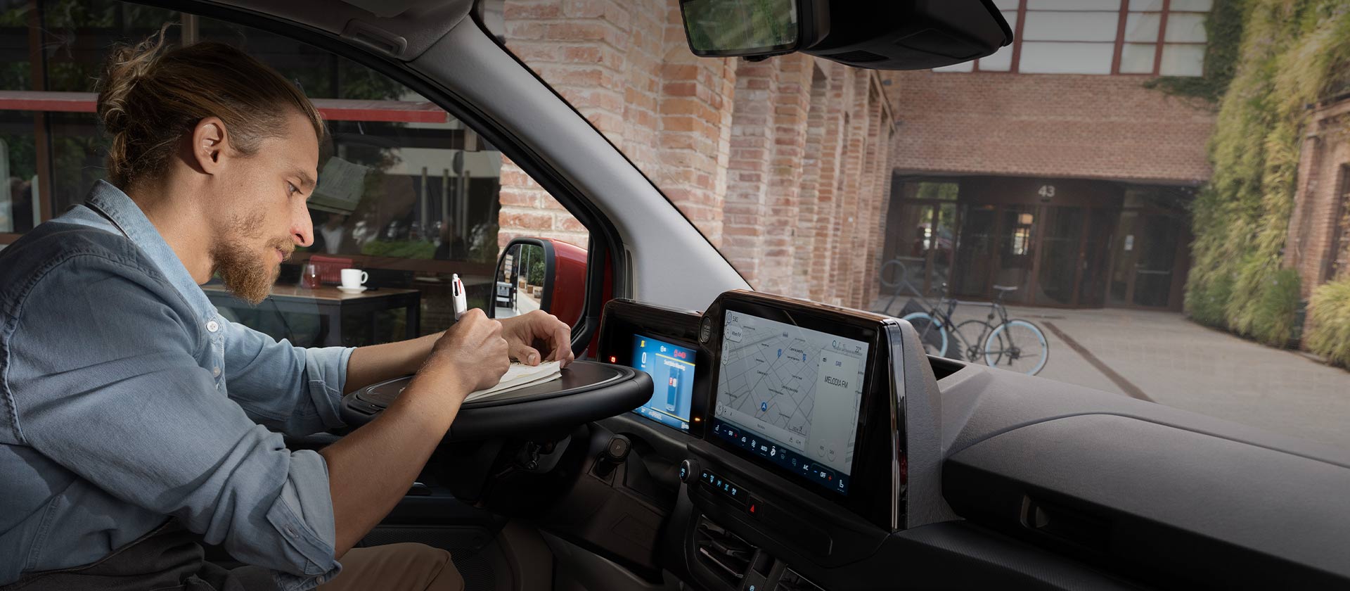 Una persona escribiendo en un cuaderno dentro de una Ford Transit Custom.