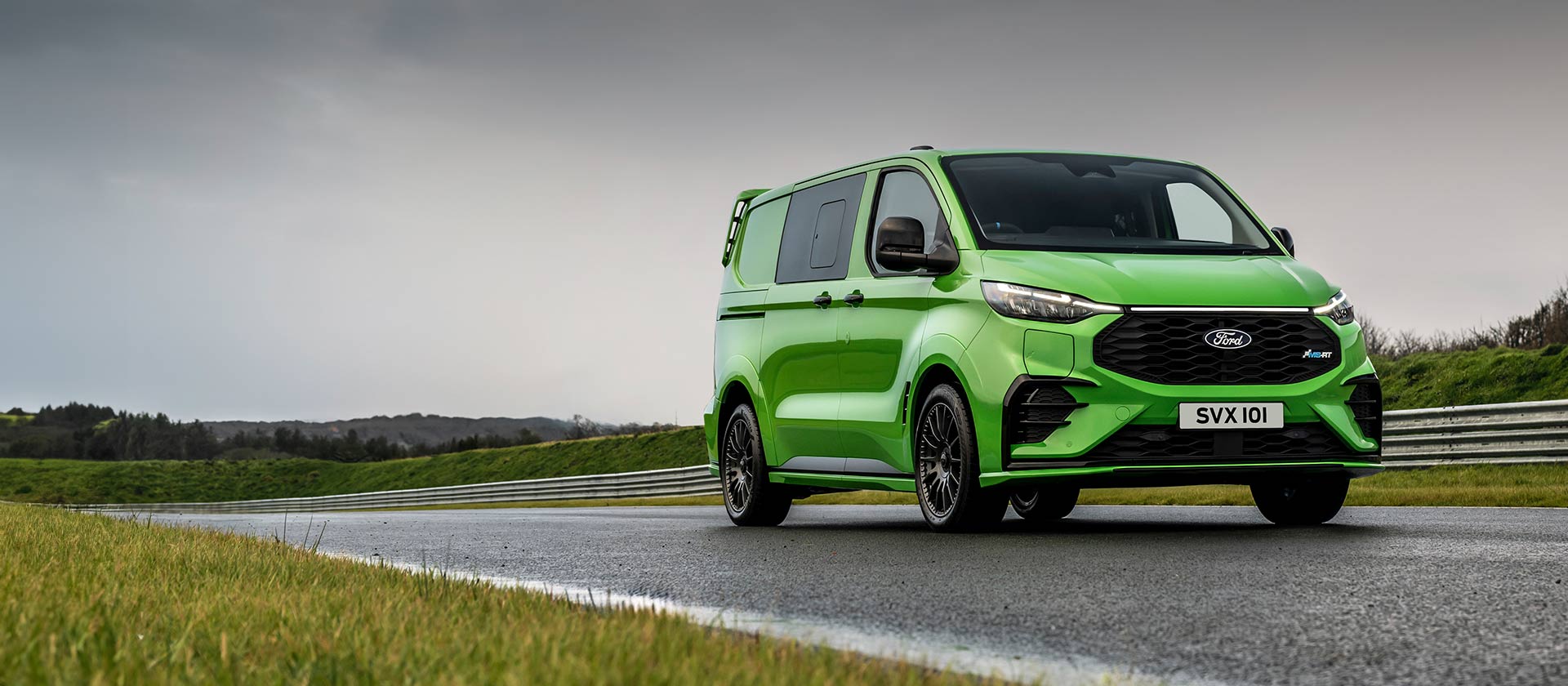 Una Ford Transit Custom MS-RT verde circulando por una pista forestal.