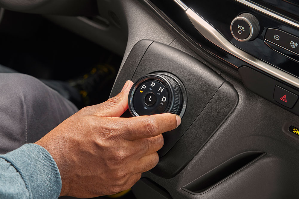 Primer plano de una mano que gira la perilla del selector de marchas en una furgoneta eléctrica Ford E-Transit.