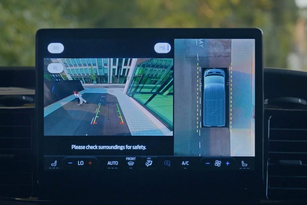 Pantalla de un panel de instrumentos que muestra una vista de arriba a abajo de una furgoneta Ford Transit con un peatón.