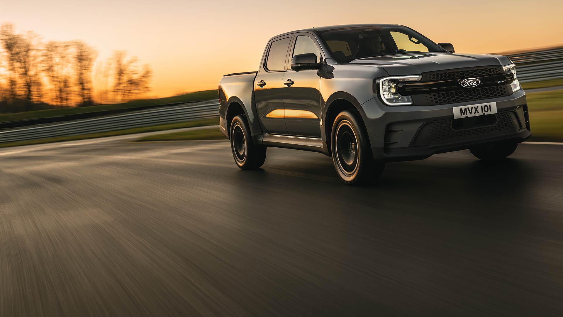 Un Ford Ranger Platinum gris oscuro recorre una pista al atardecer.