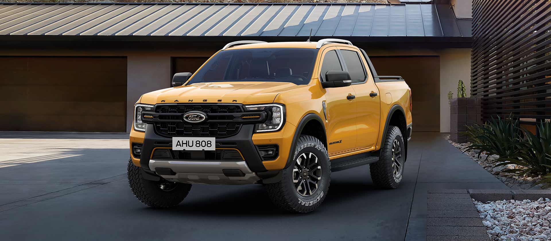 Un Ford Ranger con doble cabina amarillo estacionado frente a una casa.