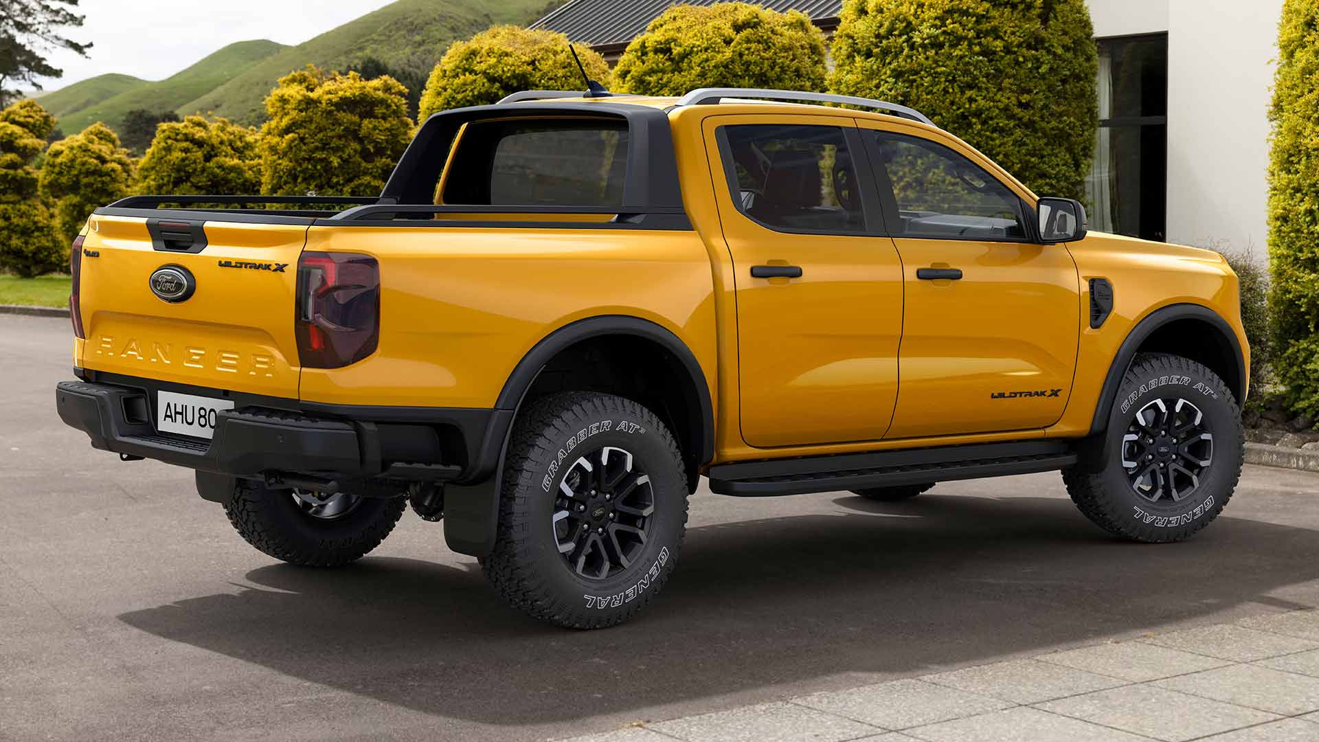 Un Ford Ranger con doble cabina amarillo estacionado en el camino de entrada a una casa.