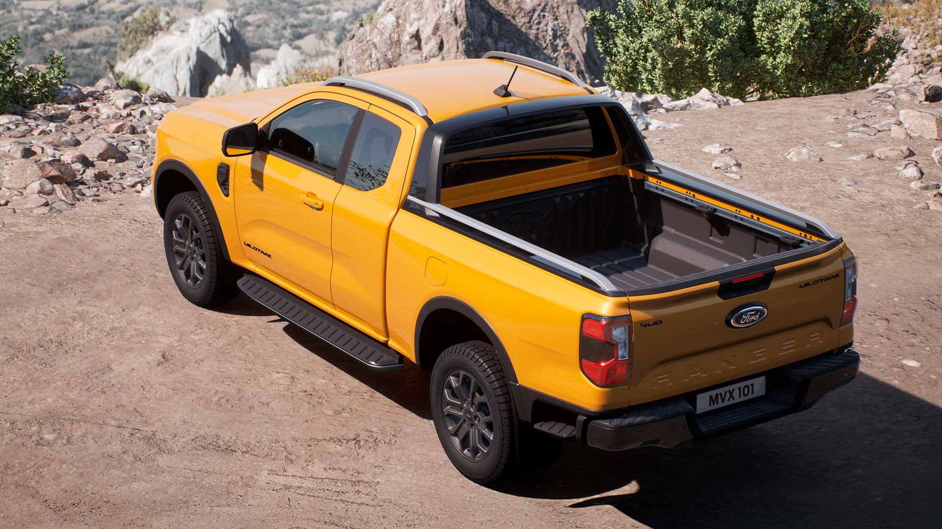 Un Ford Range Wildtrak con cabina súper amarillo, aparcado en una superficie arenosa.