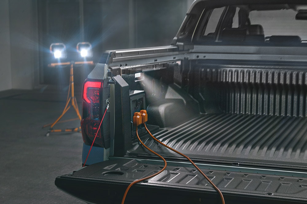 Primer plano de la caja de carga de un Ford Ranger híbrido enchufable que alimenta herramientas y elementos de iluminación con el sistema Pro Power OnBoard
