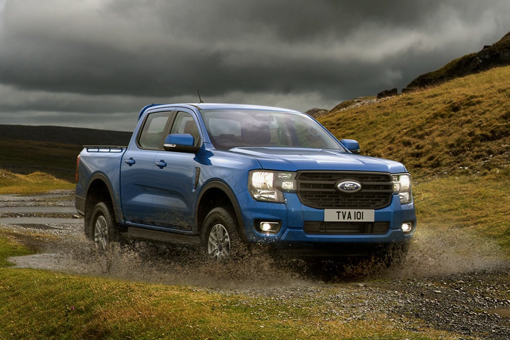 Ford Ranger azul vadeando con un paisaje accidentado de fondo.