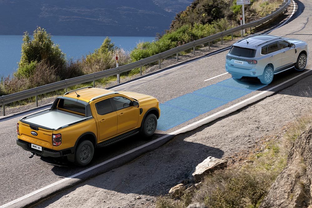  Un Ford Ranger amarillo utiliza su avanzado sistema de asistencia al conductor mientras recorre una carretera costera. 