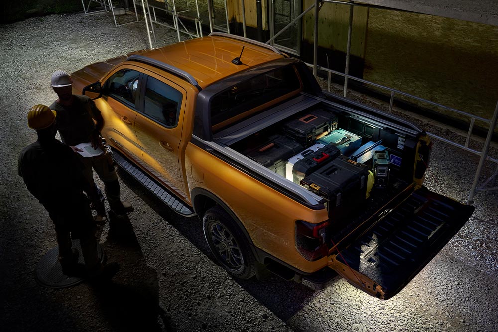 Vista superior de un Ford Ranger Wildtrak amarillo por la noche con la iluminación zonal exterior activada.