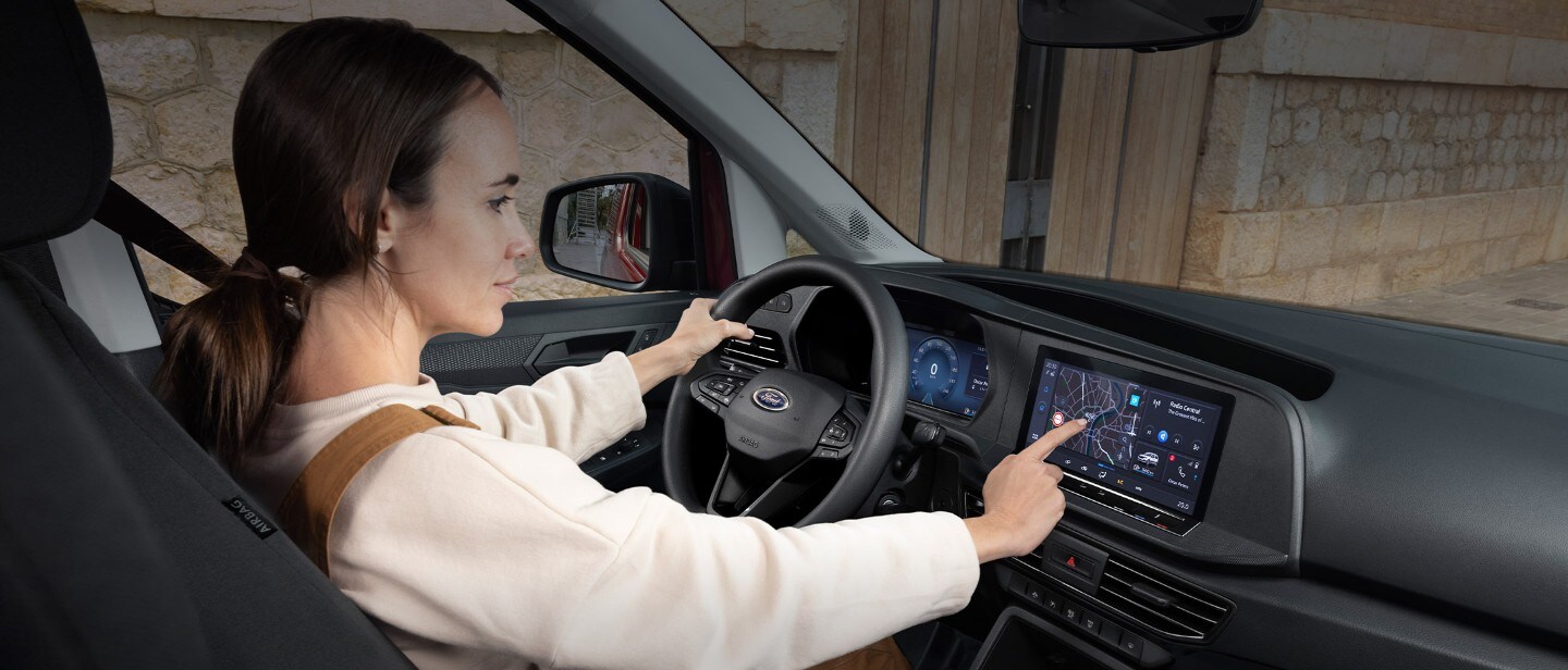 Una mujer toca la pantalla táctil de 10" sentada en el asiento del conductor de la nueva Ford Transit Connect.
