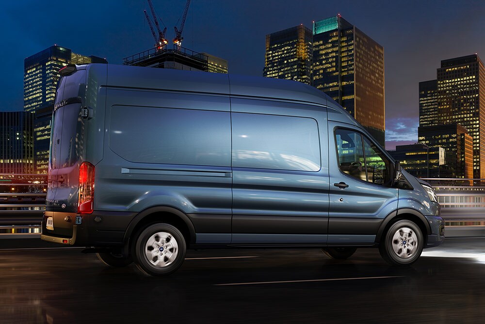 Una Ford Transit azul recorre una vía urbana de noche. 
