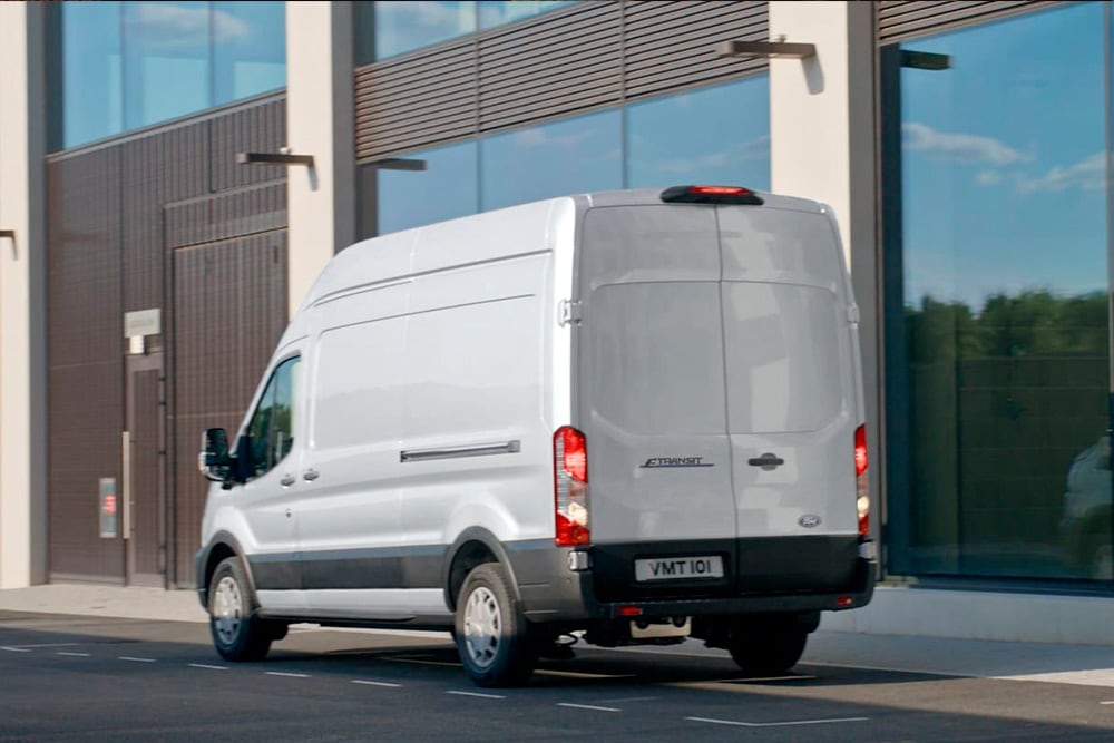 Parte trasera de una furgoneta Ford Transit plateada aparcada en una calle de la ciudad.