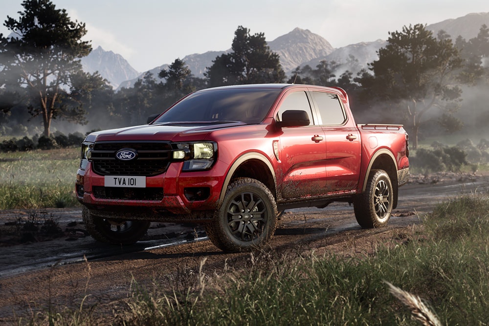 Una Ford Ranger Raptor roja circula por un camino de tierra a través de un paisaje pintoresco.