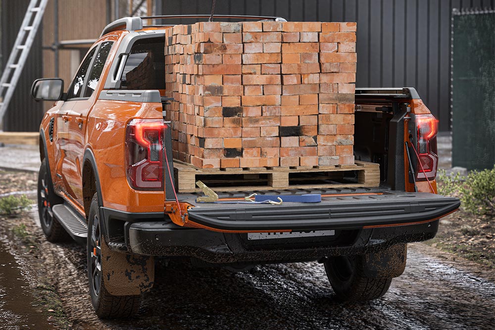 Vista de la parte trasera de una Ford Ranger de color naranja, con una montón de ladrillos apilados en la plataforma de carga.