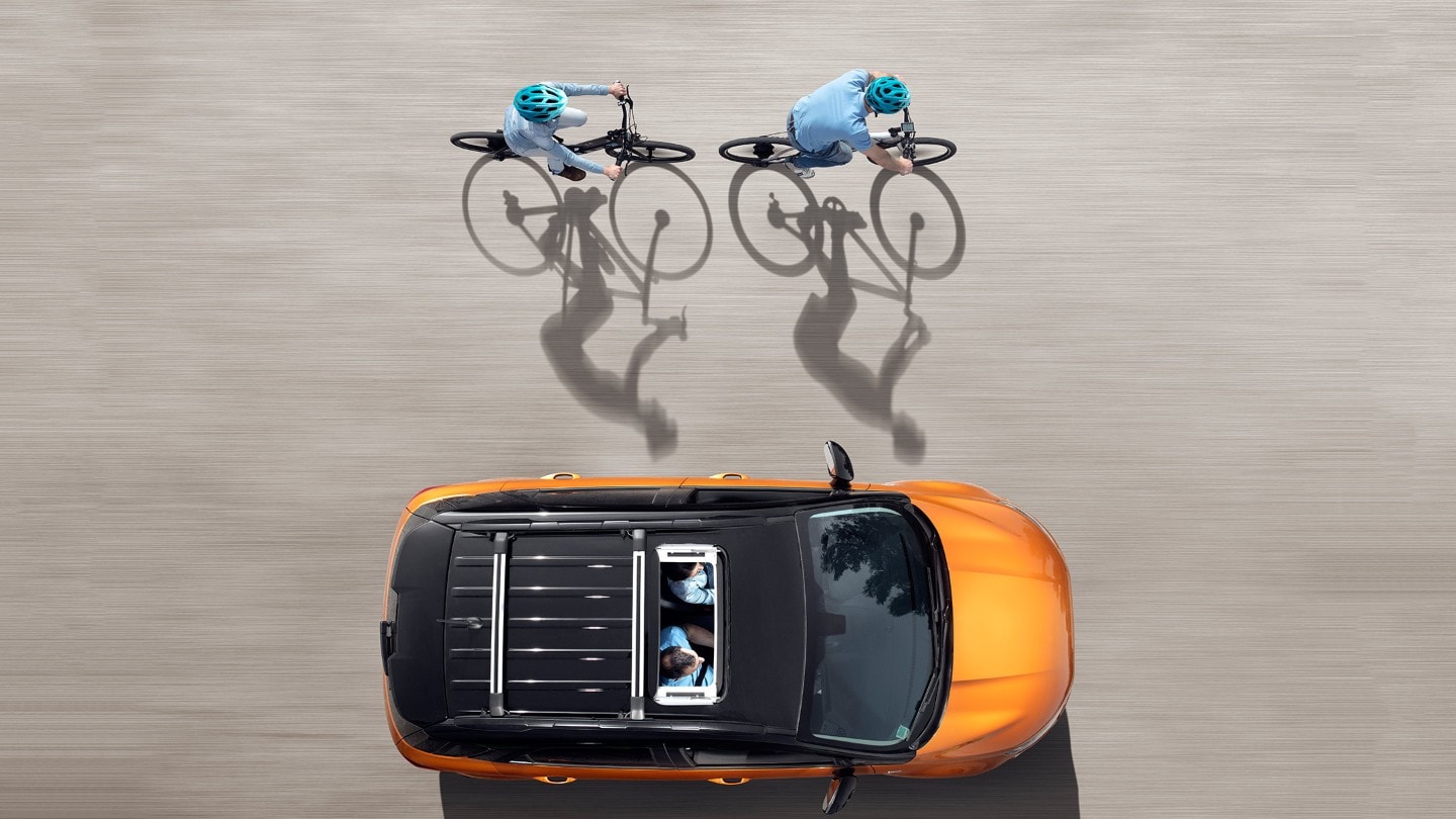Two men on the bicycles next to the car