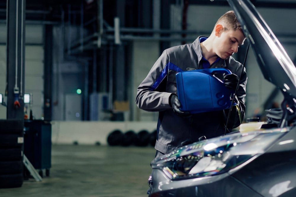 Vista lateral de un técnico autorizado por Ford realizando reparaciones en un vehículo en un taller.