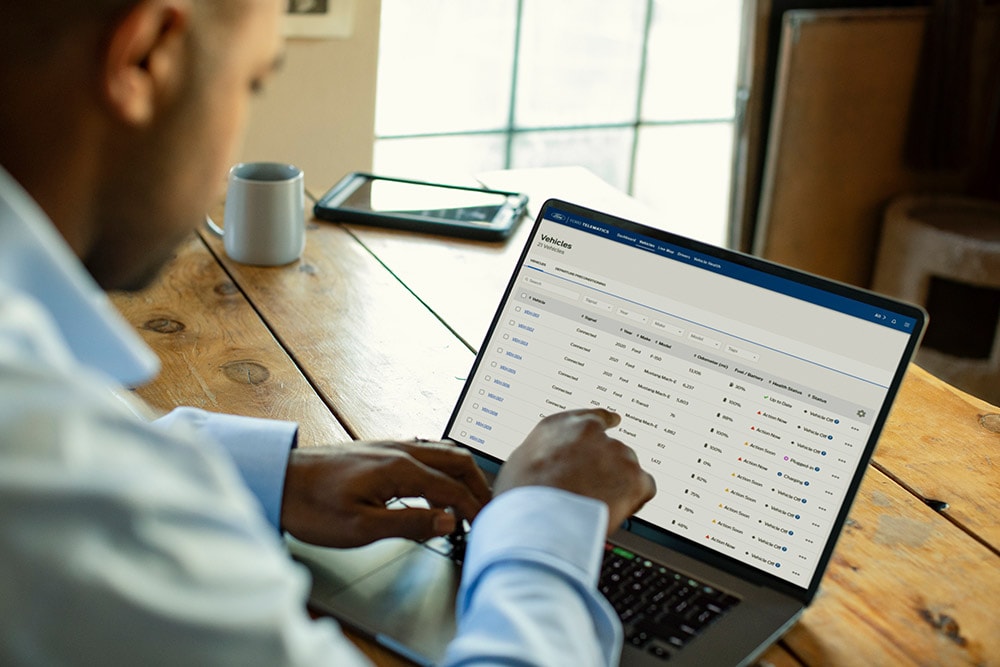Un gerente de flota de Ford Pro viendo datos del vehículo en su portátil.