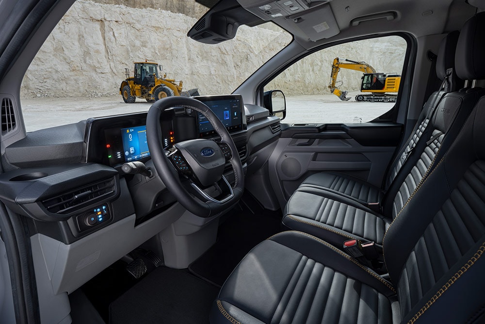 Vista interior de una furgoneta Ford Transit Custom, que muestra el panel de instrumentos, el volante y los asientos.