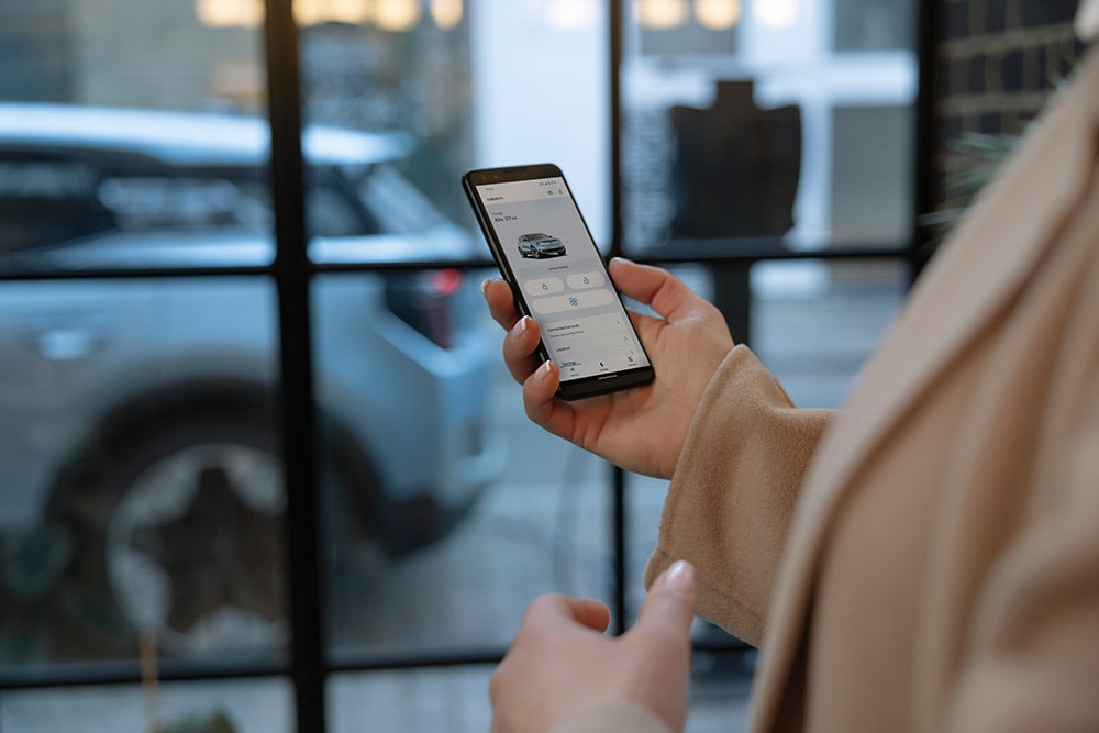 Una persona con un móvil que muestra la aplicación FordPass con información de gestión de una flota.
