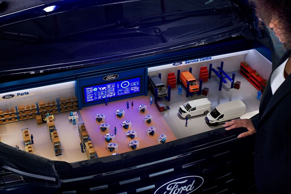 Modelo en miniatura de un centro de servicio Ford dentro del maletero de un coche.