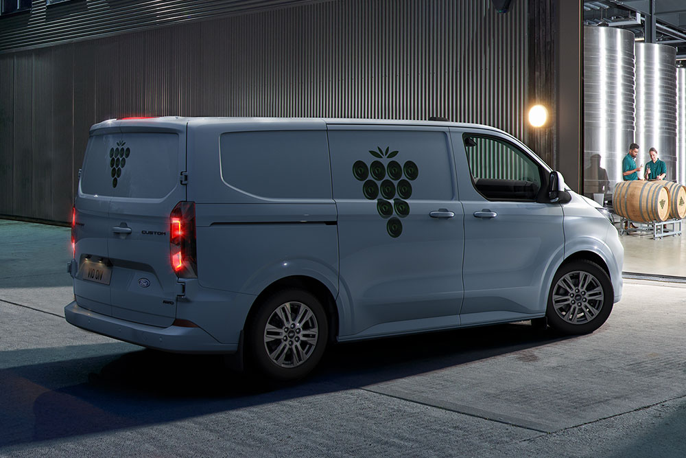  Una furgoneta Ford blanca aparcada frente a la puerta de un almacén por la noche.