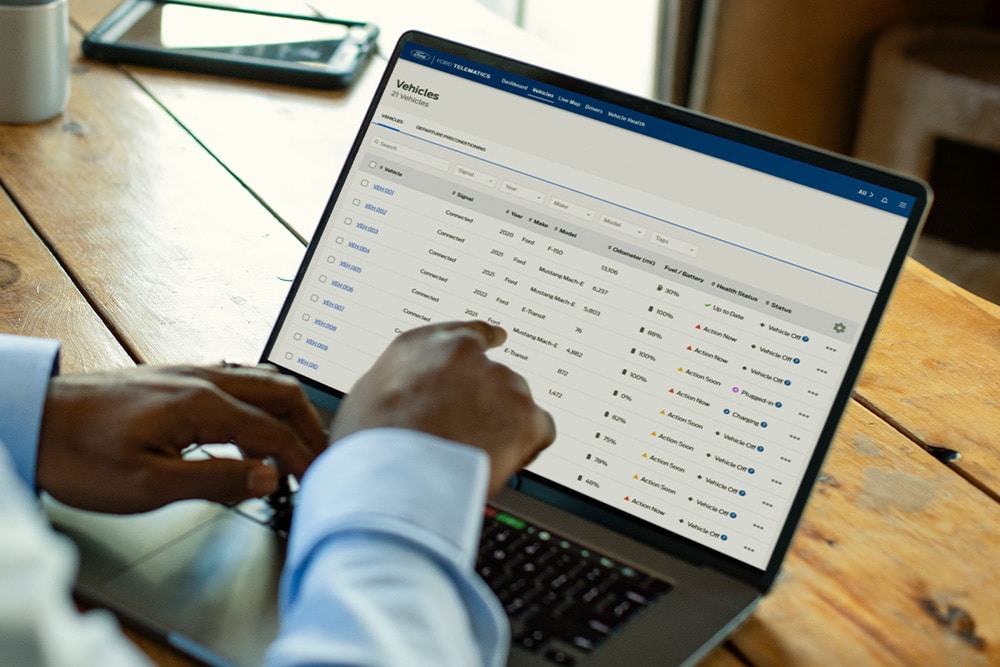 Un gerente de flota de Ford Pro viendo datos del vehículo en su portátil.