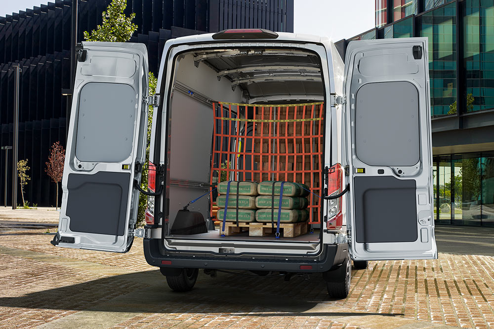 Una vista trasera del interior de una furgoneta Ford blanca aparcada cerca de edificios de oficinas.