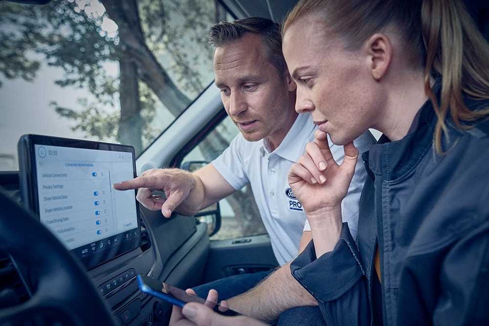Varios vehículos eléctricos de la flota Ford aparcados frente a un almacén.