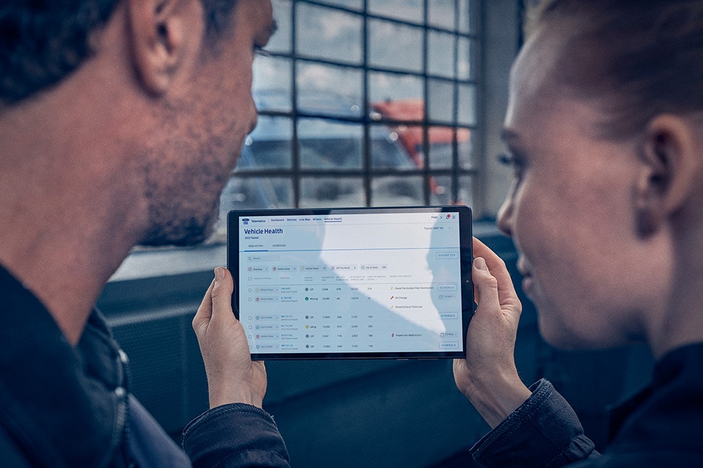 Gerentes de flota mirando la telemática del vehículo en una tablet.