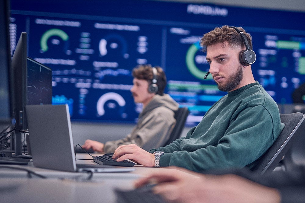 Un trabajador de Ford con auriculares y trabajando en su portátil.