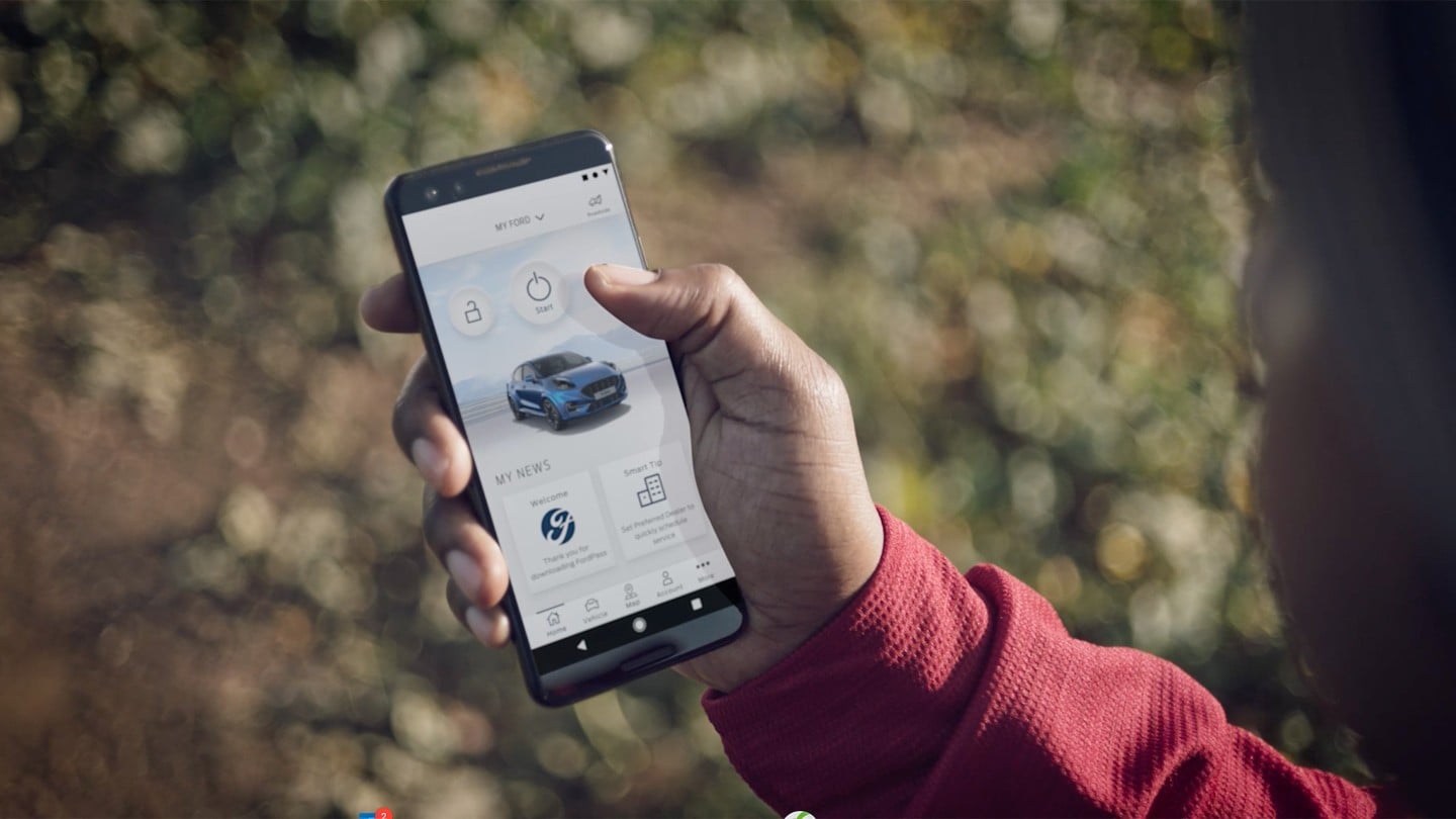 Man holding a phone using remote locking on the FordPass App