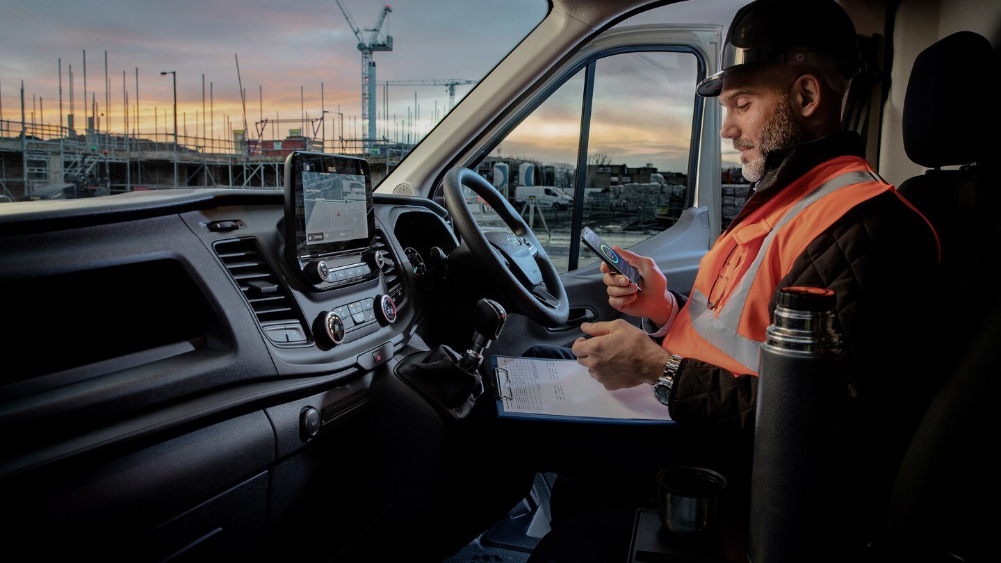 Worker sitting in a Transit Van looking at a smartphone