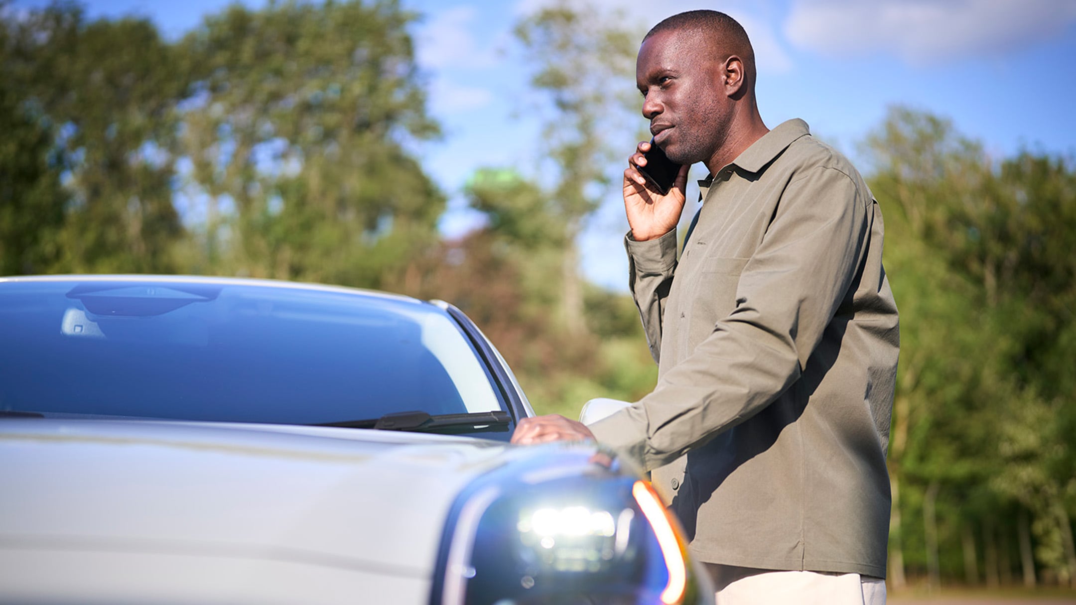 Una persona coloca un triángulo de advertencia junto a un coche averiado en una carretera.