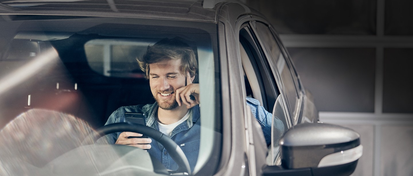 Man in drivers seat of a ford vehicle, on his phone