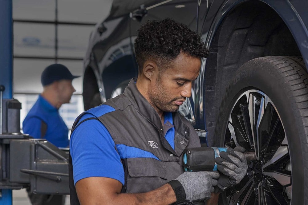 Un técnico de Ford aprieta los pernos de la rueda de un vehículo durante una revisión.