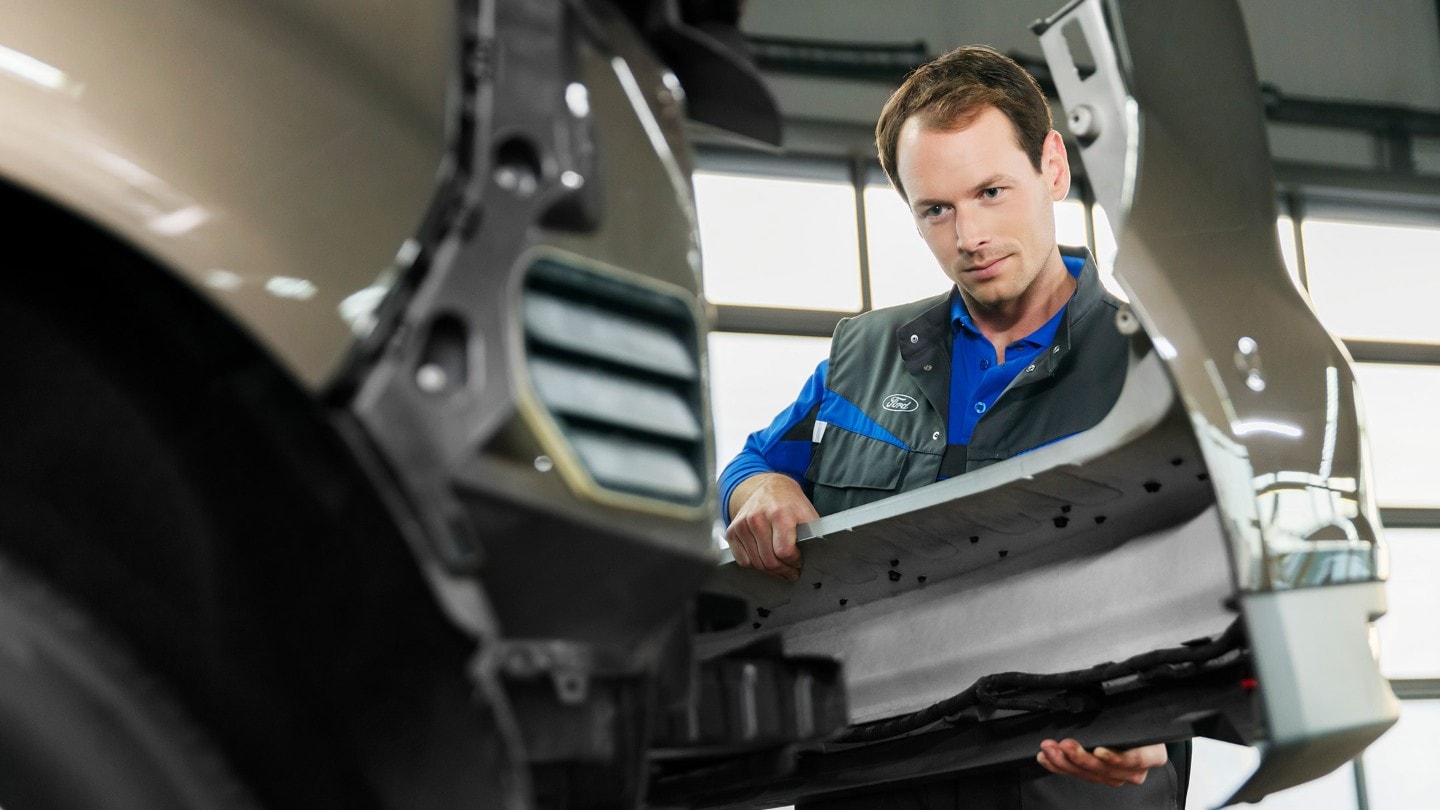 Técnico de servicio de Ford cambiando un parachoques delantero