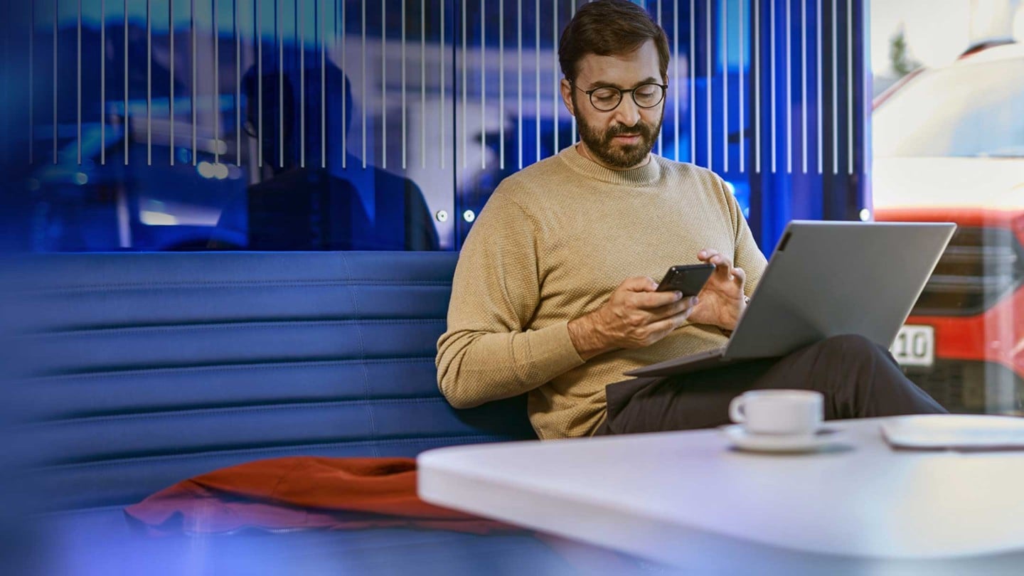 Una persona sentada en un escritorio con portátil y smartphone en una oficina moderna.